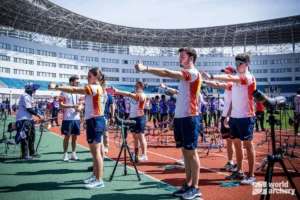 El equipo nacional de tiro con arco español están haciendo un ejercicio con la visión en el calentamiento con el pulgar hacia arriba y los brazos levantandos