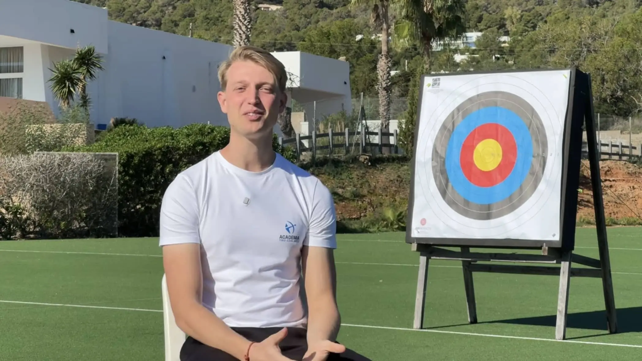 Javier Mérida con una diana detrás presentando un episodio del podcast de tiro con arco de la Academia.